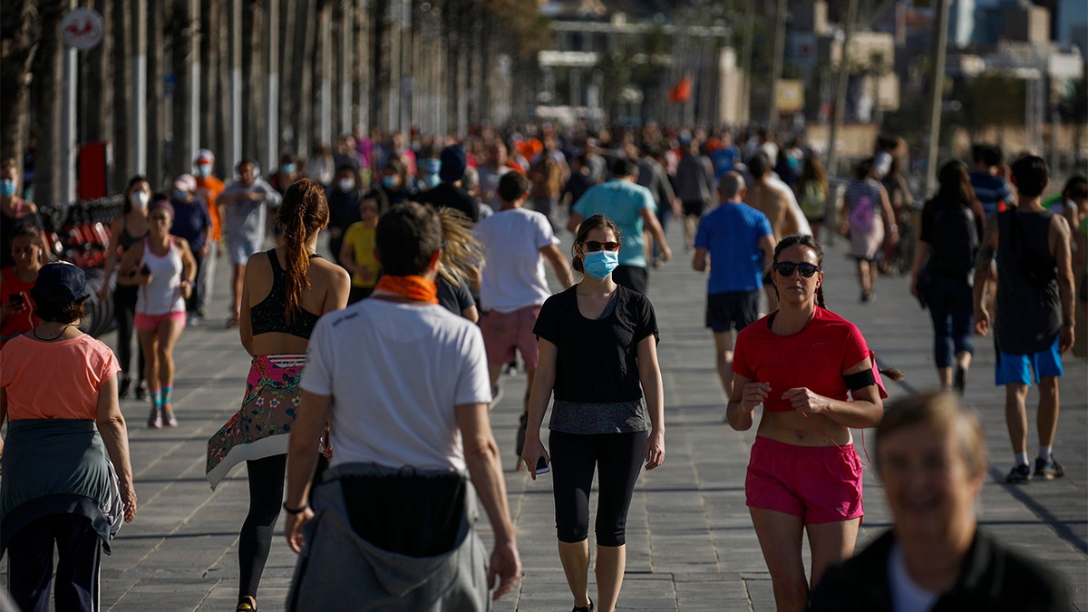 People exercises in a seafront promenade in this photo taken with a telephoto lens in Barcelona, Spain, Saturday, May 2, 2020. Spaniards have filled the streets of the country to do exercise for the first time after seven weeks of confinement in their homes to fight the coronavirus pandemic. People ran, walked, or rode bicycles under a brilliant sunny sky in Barcelona on Saturday, where many flocked to the maritime promenade to get as close as possible to the still off-limits beach. (AP Photo/Emilio Morenatti)
