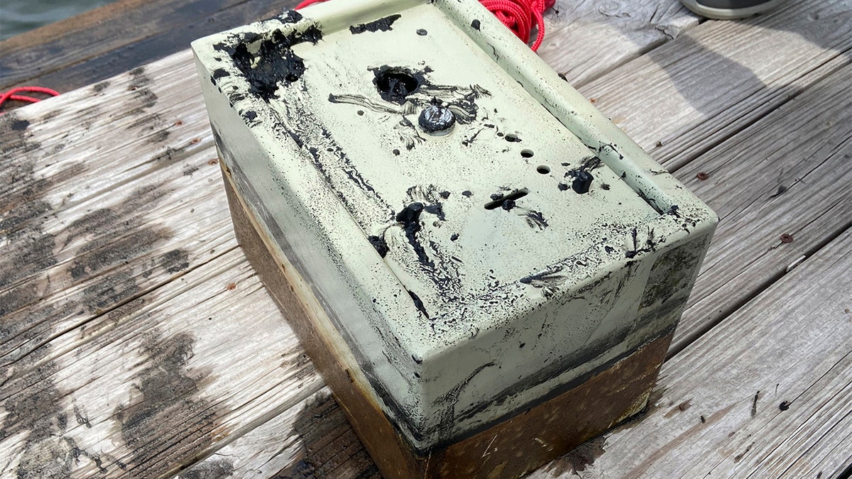 In this May 9, 2020, photo provided by Catherine Brewer, is a safe that Knox Brewer pulled out of Whitney Lake in South Carolina. The 6-year-old was using a magnet attached to a string to fish for metal in the water when he reeled in a lockbox that police said was stolen from a woman who lived nearby eight years ago. (Catherine Brewer via AP)