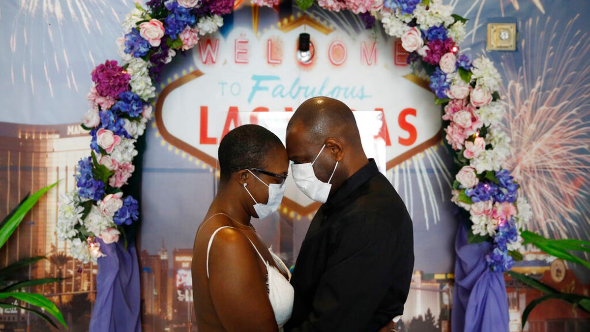 LaTahja Frazier, left, and Laborskie Frazier pose for their wedding photographer after getting married at The Little Neon Chapel, Sunday, May 10, 2020, in Las Vegas. (AP Photo/John Locher)