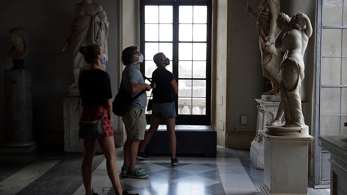 Visitors wearing a face masks to prevent the spread of COVID-19 admire statues in the Rome Capitoline Museums, including the second century A.D. Roman marble statue "Cupid and Psyche", at right, Tuesday, May 19, 2020. (AP Photo/Alessandra Tarantino)
