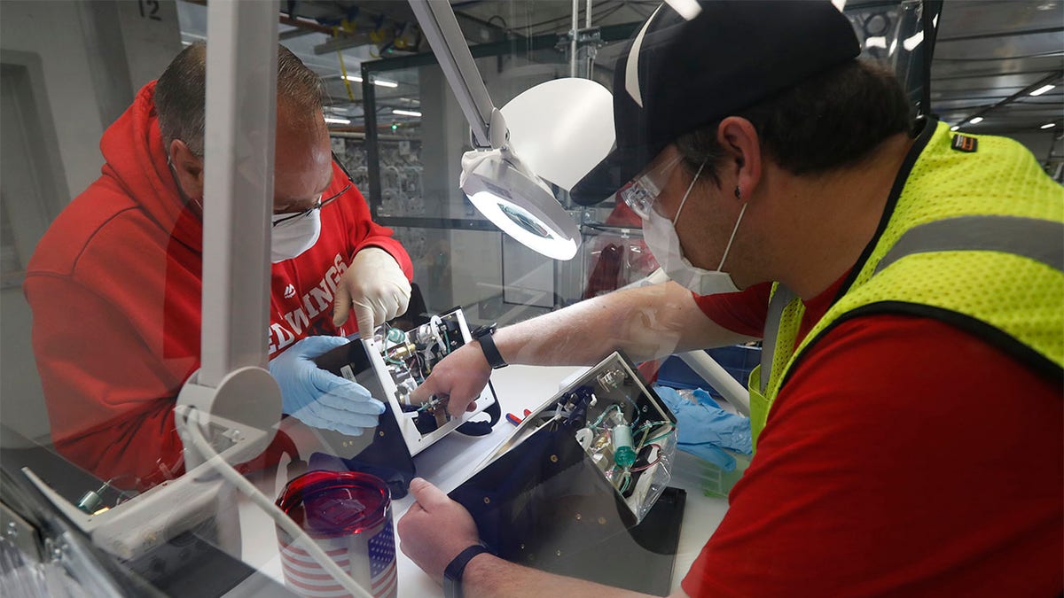 Ford Motor Co., team leader Kyle Lenart, right, inspects a ventilator that the automaker is assembling at the Ford Rawsonville plant, Wednesday, May 13, 2020 in Ypsilanti Township, Mich. The plant was converted into a ventilator factory, as hospitals battling the coronavirus report shortages of the life-saving devices. The company has promised to deliver 50,000 by July 4. Lenart is volunteering to make ventilators at the plant outside Detroit that, beginning Monday, will phase back into producing automotive components. (AP Photo/Carlos Osorio)