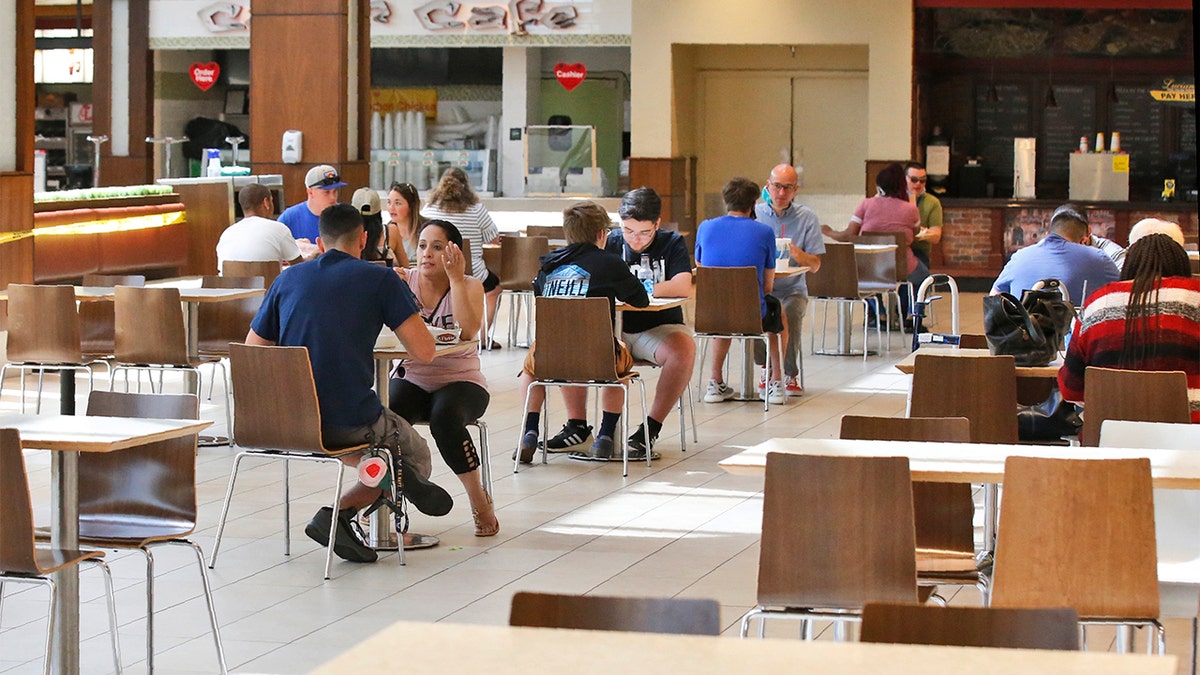People eat in the food court at Penn Square Mall as the mall reopens Friday, May 1, 2020, in Oklahoma City. The tables in the food court have been thinned out, reducing capacity from from 600 to 170 seats.