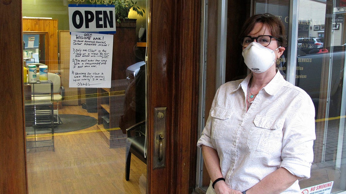 Barber Rhonda Adams poses outside her shop shop in downtown Juneau, Alaska, on April 24 after some businesses were allowed to reopen. Adams said she was excited to get back to work. (AP Photo/Becky Bohrer)