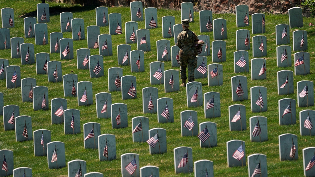 FILE -- May 23, 2019:An Old Guard takes part in "Flags-In", an annual event where a small American flag is placed in front of more than 240,000 headstones of U.S. service members buried at Arlington National Cemetery in Arlington, Va. (REUTERS/Kevin Lamarque)