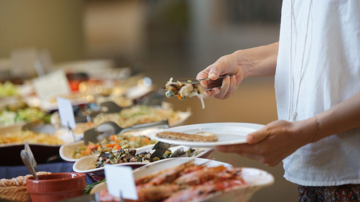 Woman taking food from a buffet line