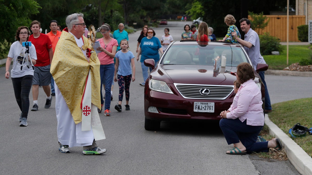 Using social distancing due to the COVID-19 pandemic, the Rev. Pat O'Brien of St.Pius X Catholic Church leads a Eucharistic procession through a neighborhood near his church in San Antonio, April 27. Texas Gov. Greg Abbott said churches and other places of worship will be able to expand capacity as long as they continue to use safe distancing practices. (AP Photo/Eric Gay)