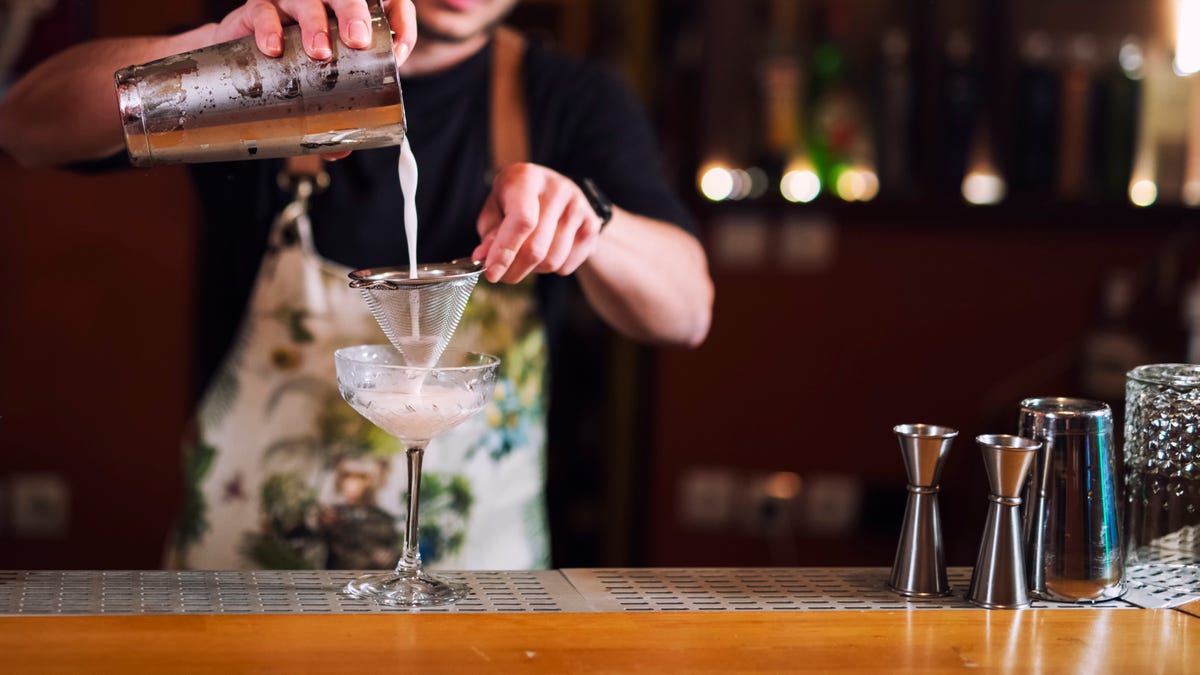 Male bartender pouring alcohol in glass, A young bartender making luxury cocktail.