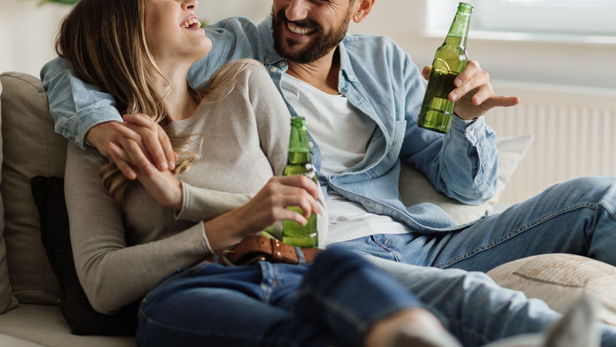 Cheerful couple having fun while drinking beer at home