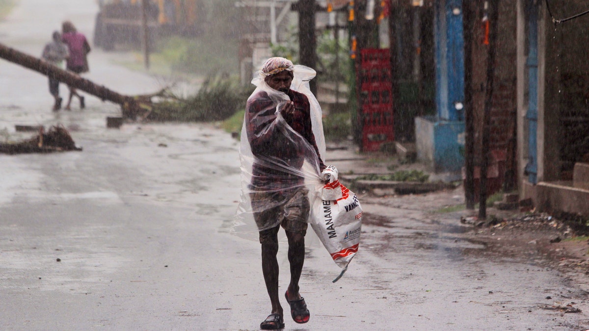 A man covers himself with a plastic sheet and walks in the rain ahead of Cyclone Amphan landfall, at Bhadrak district, in the eastern Indian state of Orissa, May 20, 2020.