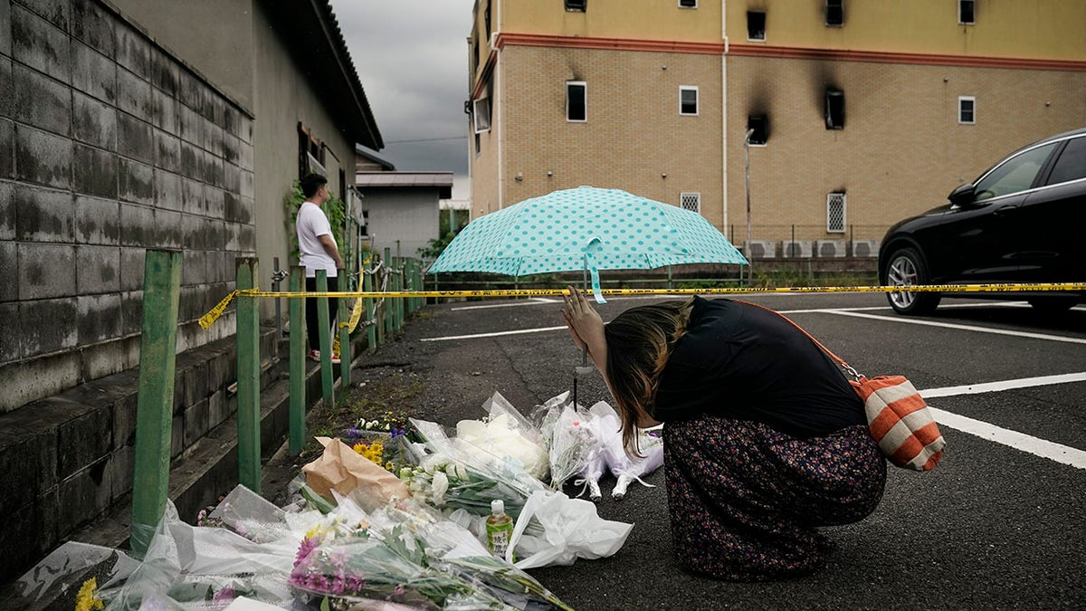 In this July 19, 2019, file photo, a woman prays at a makeshift memorial to honor the 36 victims of a fire at the building of Kyoto Animation's No. 1 studio. (AP Photo/Jae C. Hong, File)