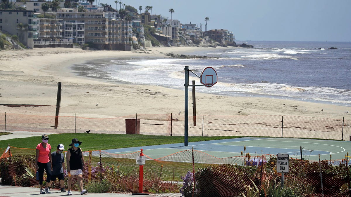 Residents walk past a closed off beach, in Laguna Beach, Calif., on Sunday. The cities of Laguna Beach and San Clemente reopened their beaches this week after they submitted plans to avoid overcrowding and allow for physical distancing in an effort to prevent the spread of the coronavirus. (AP Photo/Marcio Jose Sanchez,File)