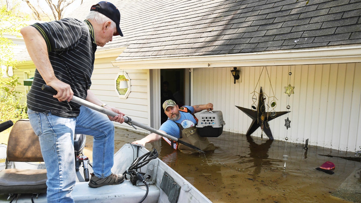 Don Thomas of Saginaw pulls his boat up to his son Jason Thomas who went back to his house near W. Signet in Midland to retrieve his families two cats. Flooding along the Tittabawassee River in downtown Midland, Mich., on May 20.