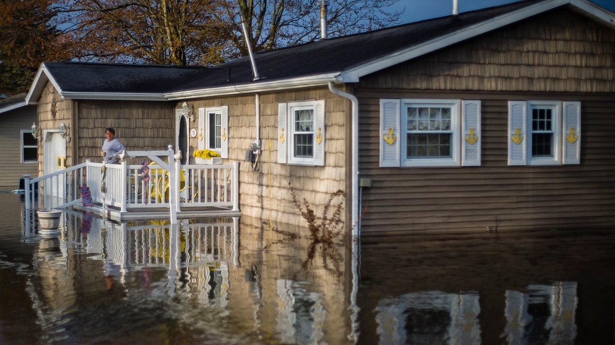 Carol Ouellette stands on her front porch, surrounded by floodwater, Tuesday, May 19, 2020 in Beaverton, Mich.