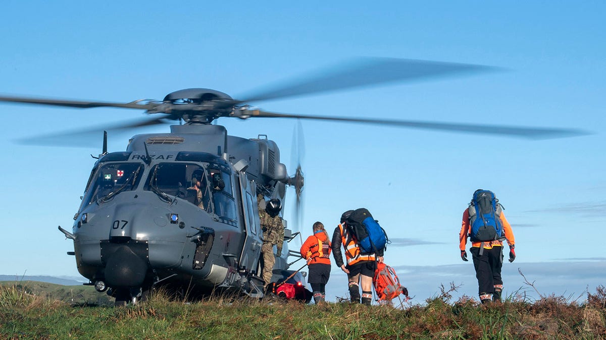 A helicopter waits as search and rescue workers board during a rescue operation to find two missing trampers in the Kahurangi National Park in the South Island of New Zealand, on Wednesday.(CPL Naomi James/New Zealand Defence Force via AP)