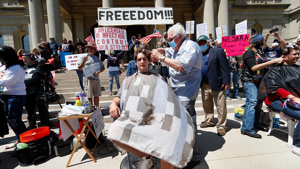 Barber Karl Manke, of Owosso, gives a free haircut to Parker Shonts on the steps of the State Capitol during a rally in Lansing, Mich., on Wednesday. (AP Photo/Paul Sancya)