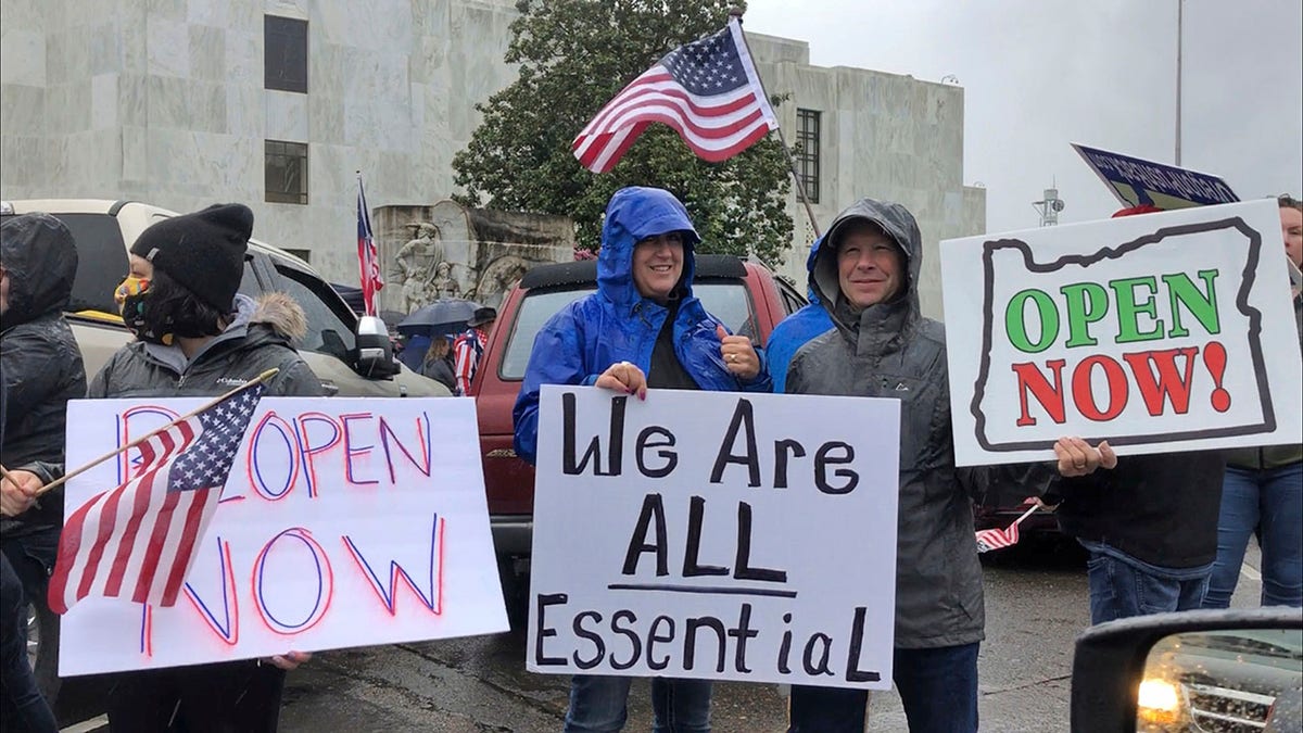 Demonstrators hold signs protesting Gov. Kate Brown's executive order that shut down much of the state's economy and imposed social distancing in her effort to stem the spread of the coronavirus. (AP Photo/Andrew Selsky)