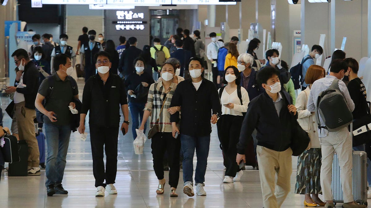 People wearing face masks arrive at the domestic flight terminal of Gimpo airport in Seoul, South Korea, on Wednesday. The quarantine authorities on Wednesday began to require all airplane passengers to wear masks amid the coronavirus pandemic. (AP Photo/Ahn Young-joon)