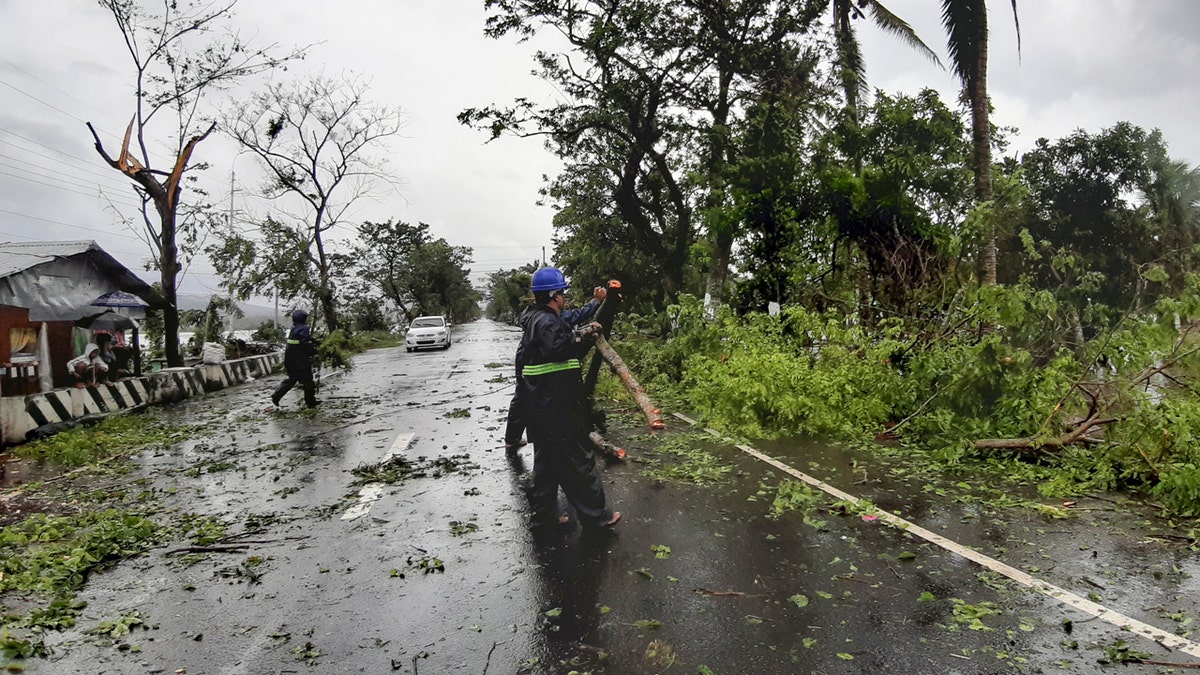 Workers clear a road of trees and branches toppled by strong winds from typhoon Vongfong as it passes by Sorsogon province, eastern Philippines on Friday May 15, 2020.