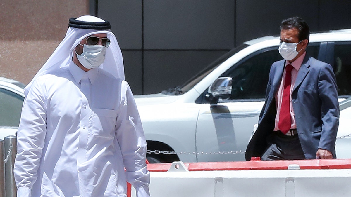 Men wearing protective masks walk by in Qatar's capital Doha, on May 17, 2020, as the country begins enforcing the world's toughest penalties for failing to wear masks in public, as it battles one of the world's highest coronavirus infection rates. - More than 30,000 people have tested positive for COVID-19 in the tiny Gulf country, 1.1 percent of the 2.75 million population, although just 15 people have died. Violators of the new rules will face up to three years in jail and fines of as much as $55,000. (Photo by KARIM JAAFAR / AFP) (Photo by KARIM JAAFAR/AFP via Getty Images)