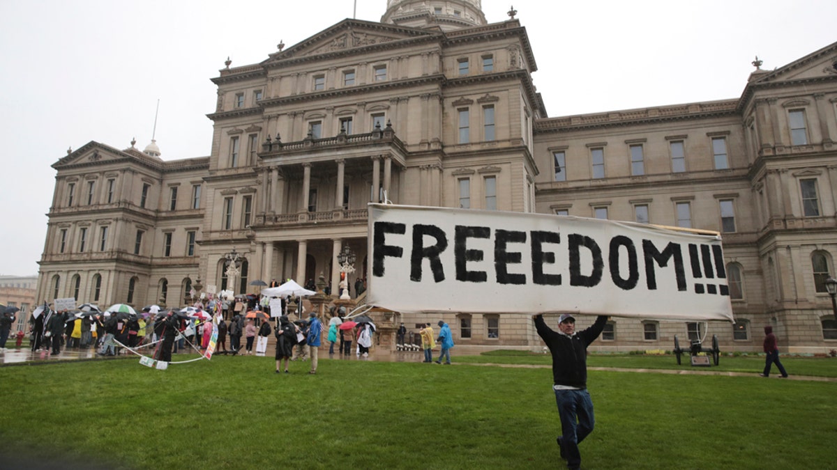 A protester carries a sign during a rally against MichiganÕs coronavirus stay-at-home order at the State Capitol in Lansing, Mich., Thursday, May 14, 2020. (AP Photo/Paul Sancya)