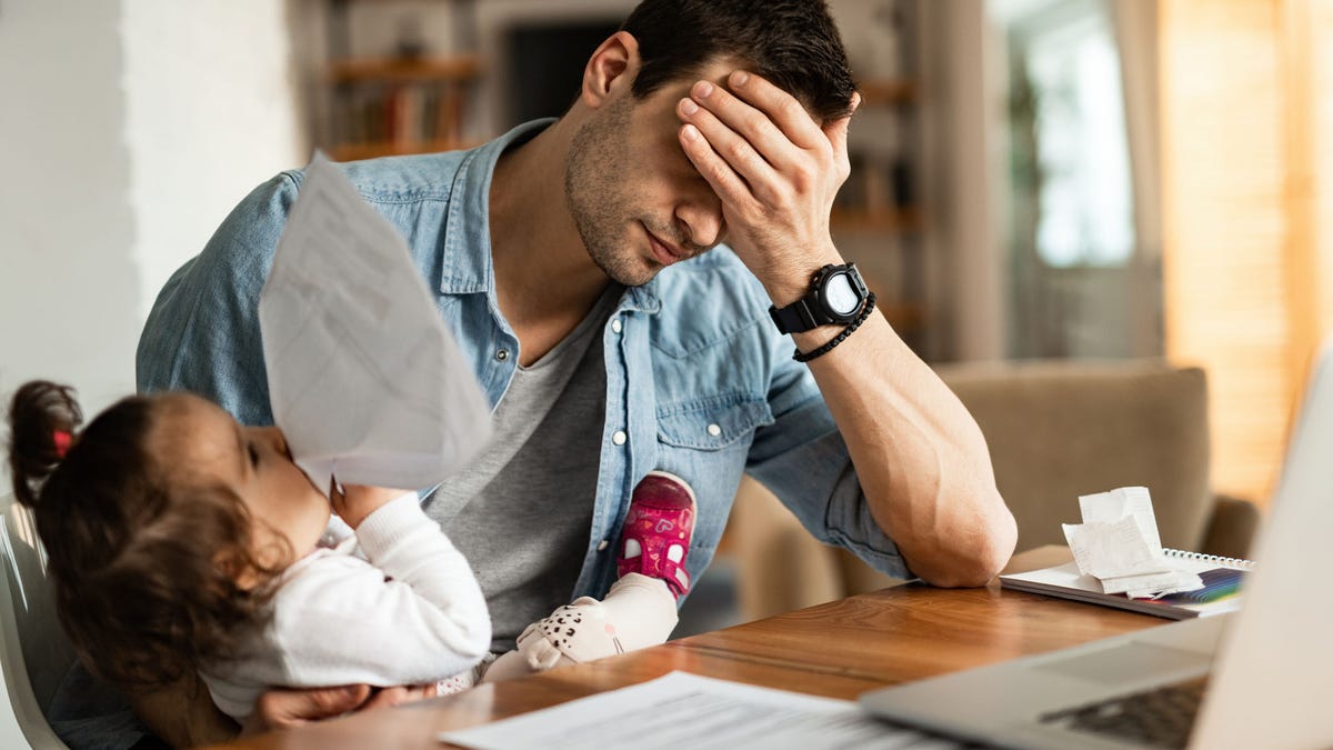 Stay at home father having a headache while babysitting and working at home.