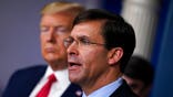 FILE - In this March 18, 2020, file photo, Defense Secretary Mark Esper speaks as President Donald Trump listens during press briefing with the coronavirus task force, at the White House in Washington. The government’s $3 trillion effort to rescue the economy from the coronavirus crisis is stirring worry at the Pentagon. Bulging federal deficits may force a reversal of years of big defense spending gains and threaten prized projects like the rebuilding of the nation’s arsenal of nuclear weapons. Esper says the sudden burst of emergency spending to prop up a stalled economy is bringing the Pentagon closer to a point where it will have to shed older weapons faster and tighten its belt. (AP Photo/Evan Vucci, File)