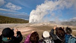 FILE - In this May 21, 2011, file photo, tourists photograph Old Faithful erupting on schedule late in the afternoon in Yellowstone National Park, Wyo. A woman has suffered burns after falling into a thermal feature at Yellowstone National Park, which is closed because of the coronavirus pandemic. Officials say she was reportedly backing up while taking photos Tuesday, May 12, 2020, and fell into a hot spring or hole where hot gases emerge near Old Faithful geyser. (AP Photo/Julie Jacobson, File)