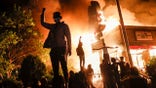 Protestors demonstrate outside of a burning fast food restaurant, Friday, May 29, 2020, in Minneapolis. Protests over the death of George Floyd, a black man who died in police custody Monday, broke out in Minneapolis for a third straight night. (AP Photo/John Minchillo)