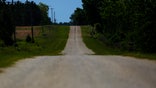 An empty road leading towards a rural countryside of Dawson, Ga., is seen on Friday, April 17, 2020, in Dawson, Ga. Of the 20 counties with the highest death rate in America, six of them are in rural southwest Georgia, where there are no packed skyrise apartment buildings or subways. Other out-of-the way places so far unscathed by the pandemic might believe, like many in Dawson once did, that the virus won't find them out there. But ambulances rushed along country roads, fields and farms in either direction, carrying COVID-19 patients to the nearest hospital, for some an hour away. (AP Photo/Brynn Anderson)