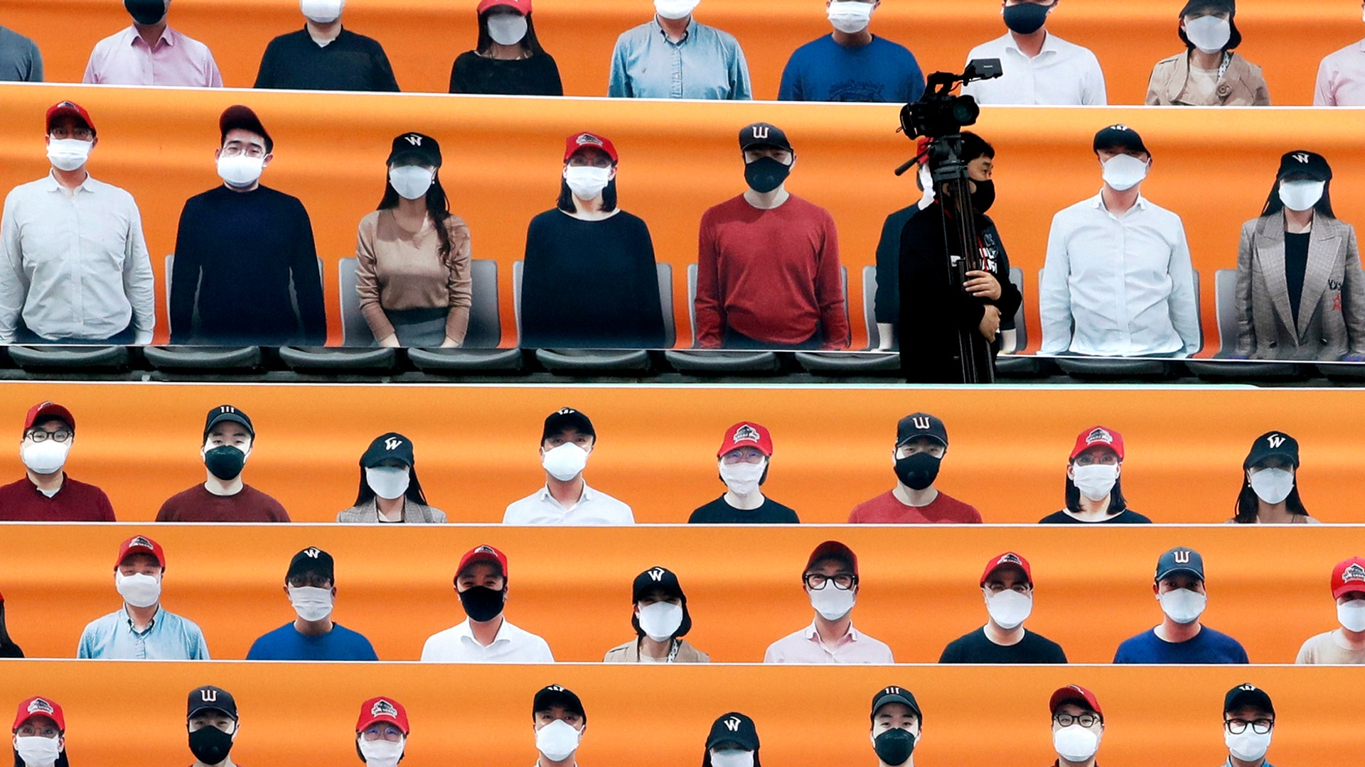 A TV cameraman walks through the spectator's seating area which is covered with pictures of fans, before the start of a regular-season baseball game in Incheon, South Korea, May 5, 2020. 