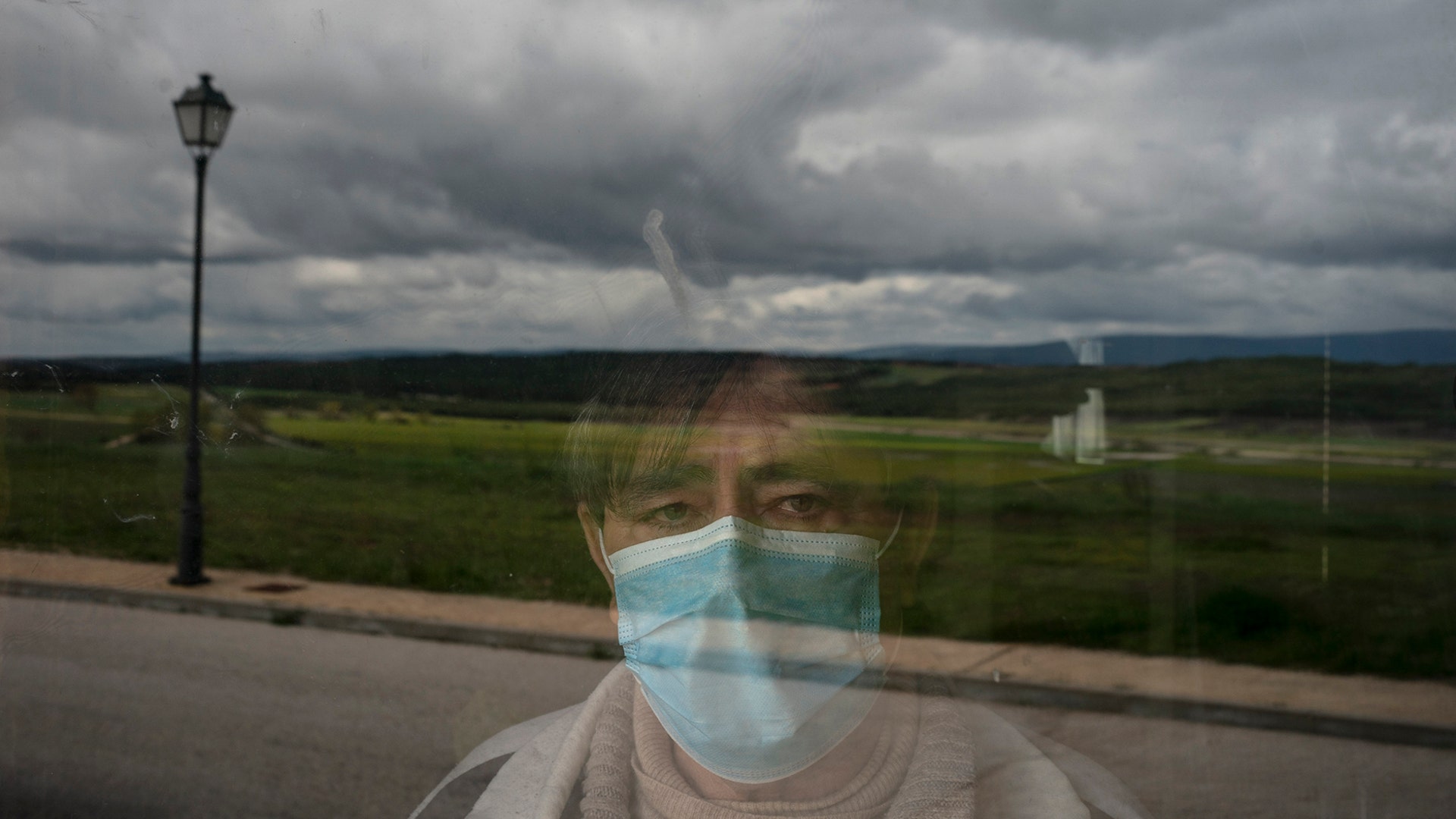 Eusebio Soria poses for a photo behind a glass door at the entrance of his home as he recovers from the coronavirus in Cabrejas del Pinar, Spain, May 2, 2020.