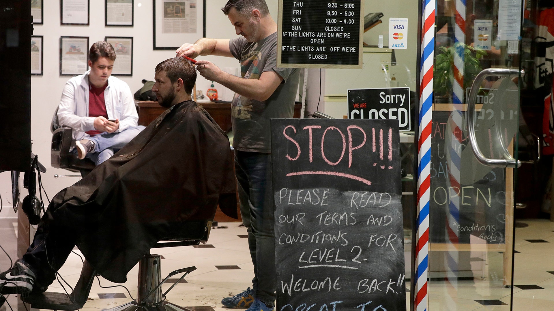 Cathedral Junction Barbers owner Conrad Fitz-Gerald cuts the hair of a customer just past midnight in Christchurch, New Zealand, May 14, 2020. 