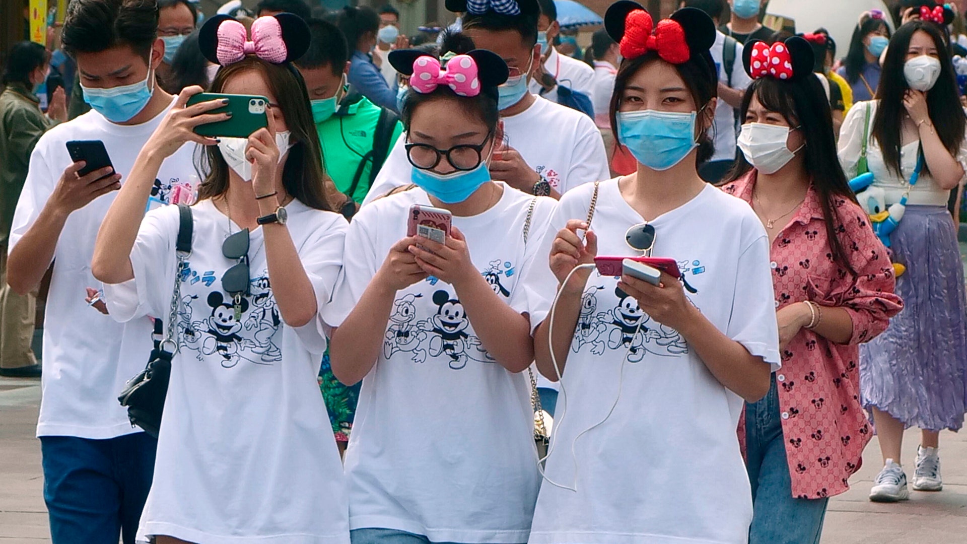 Visitors, wearing face masks, enter the Disneyland theme park as it reopened in Shanghai, May 11, 2020. 