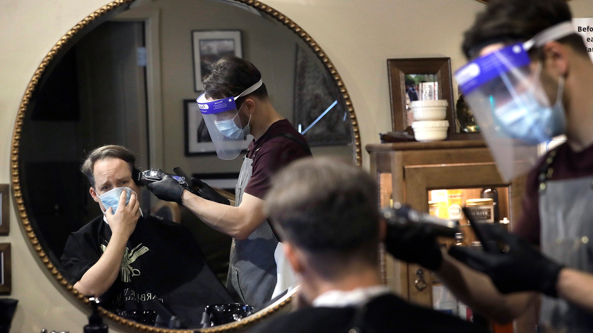 Vin Norton gets his hair cut by barber Cristian Lopez at Barber Walter's barbershop as they both wear masks in Wellesley, Mass. May 26, 2020. 