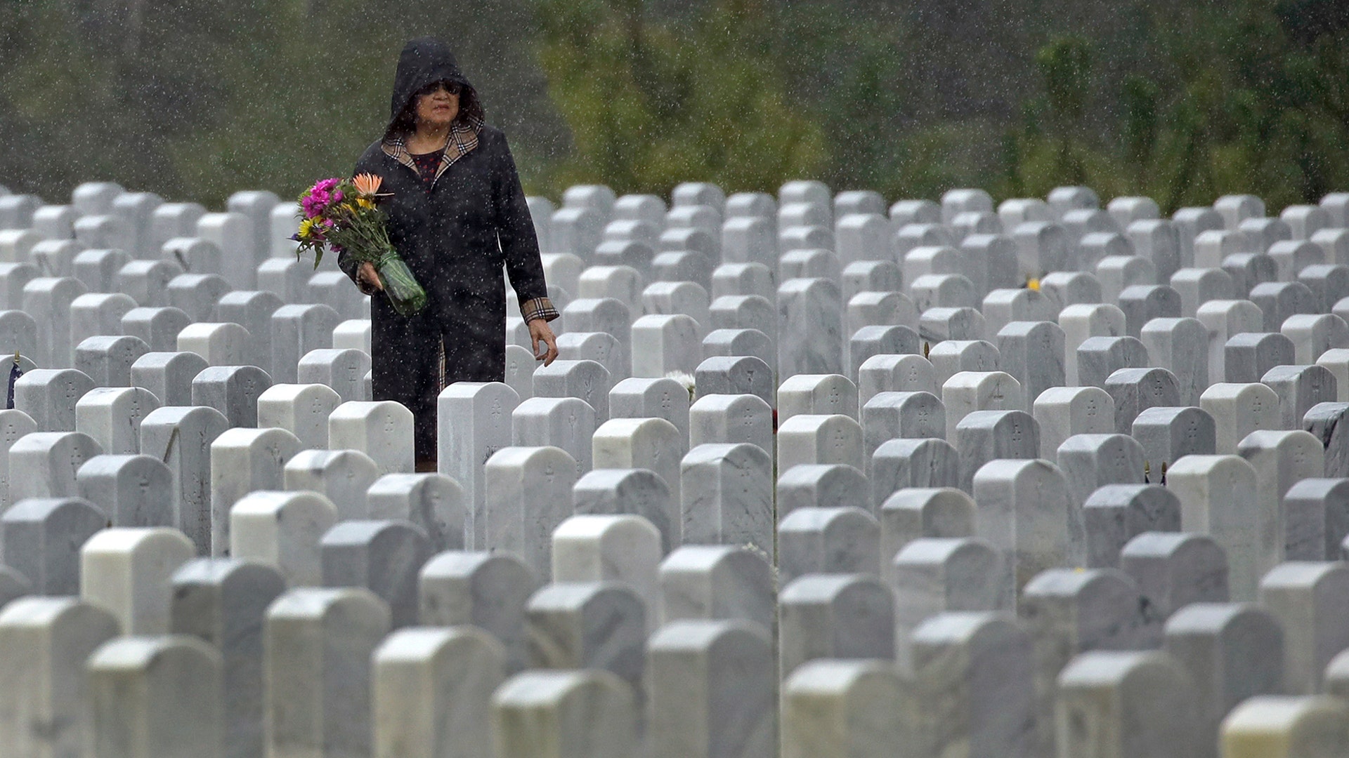A woman looks for a grave in the rain as she makes a Memorial Day visit to Cape Canaveral National Cemetery in Mims, Fla., May 25, 2020. 