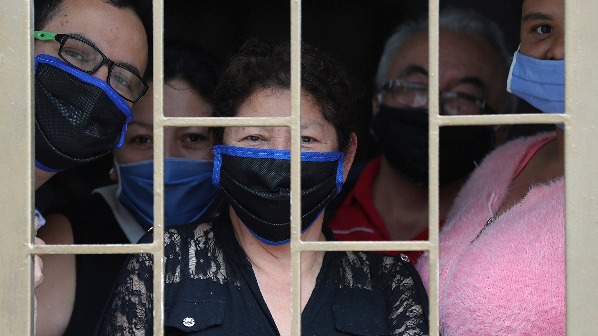 A family peers from their home's window before receiving boxes of free food during a lockdown to prevent the spread of the coronavirus in Bogota, Colombia, May 4, 2020.
