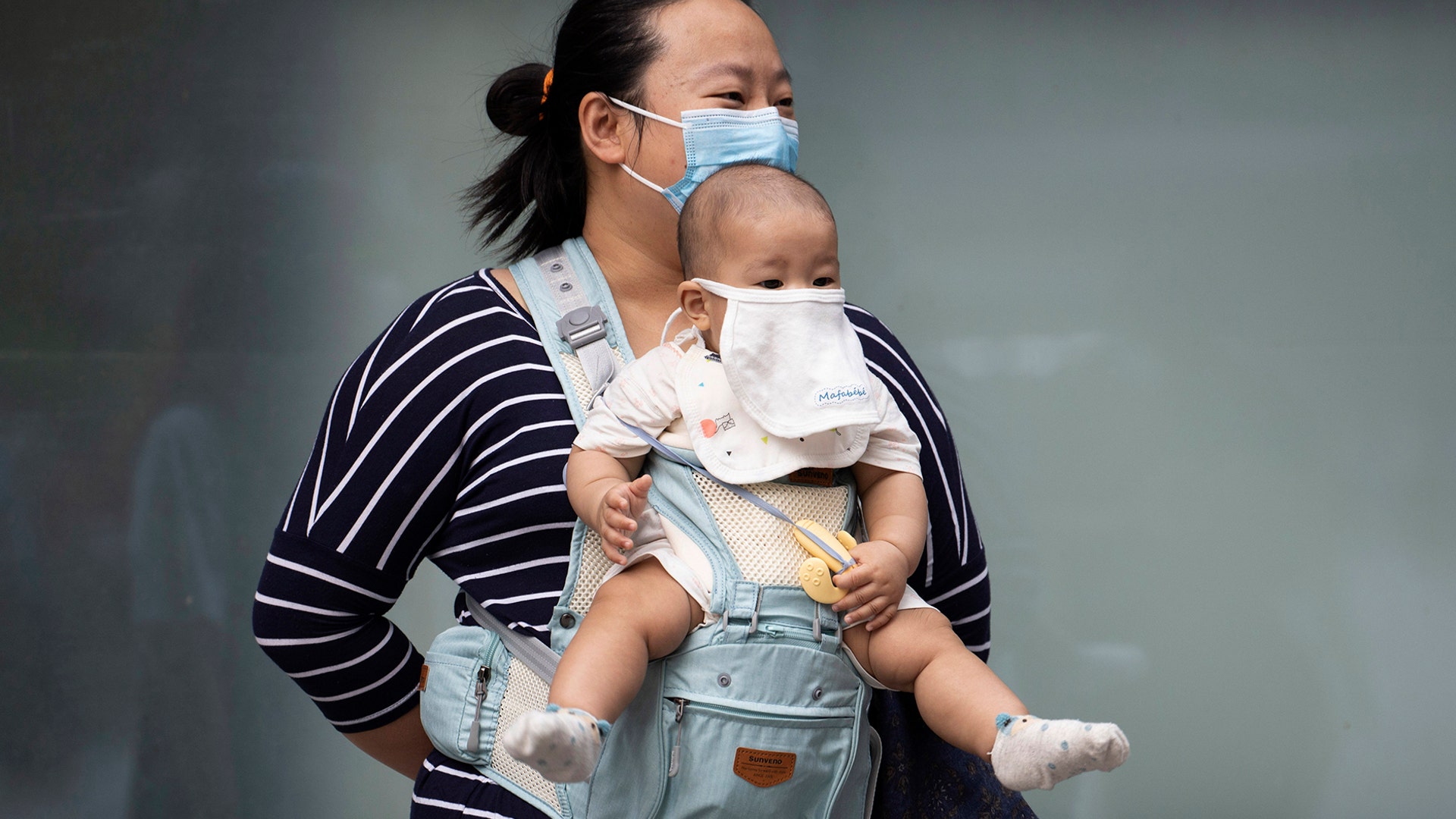 A woman and child wearing masks to help protect against the coronavirus stand out on the streets of Beijing, May 13, 2020. 