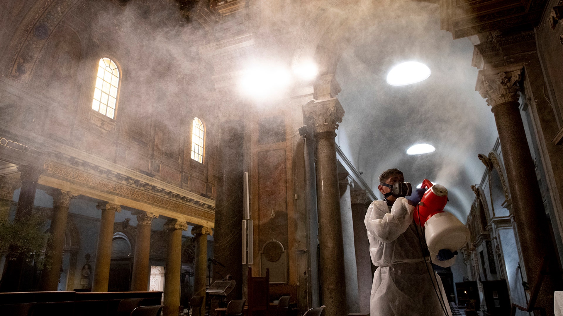 A man sprays disinfectant as he sanitizes Santa Maria in Trastevere Basilica to prevent the spread of COVID-19, in Rome, May 13, 2020. 