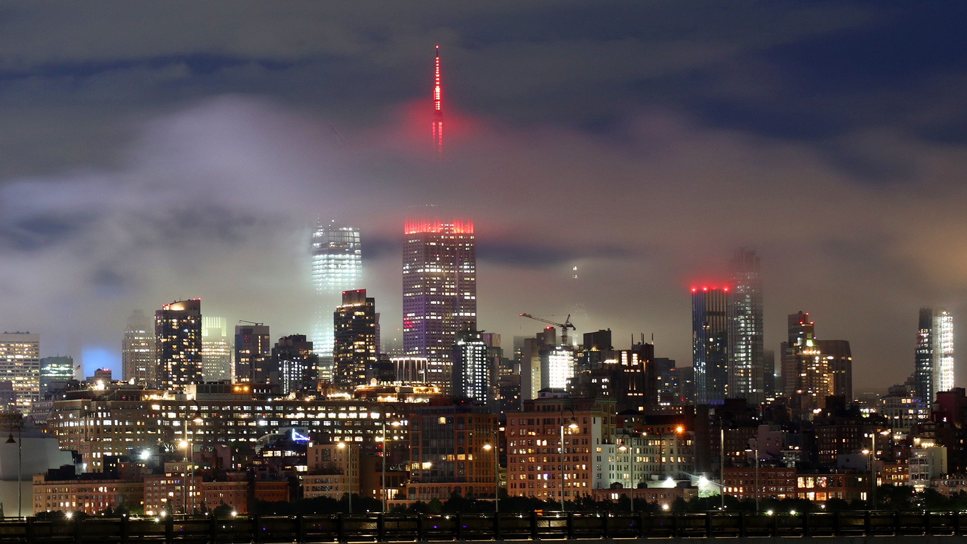 Low clouds float through midtown Manhattan past the Empire State Building lit in red to honor COVID-19 health care workers in New York City, May 27, 2020.