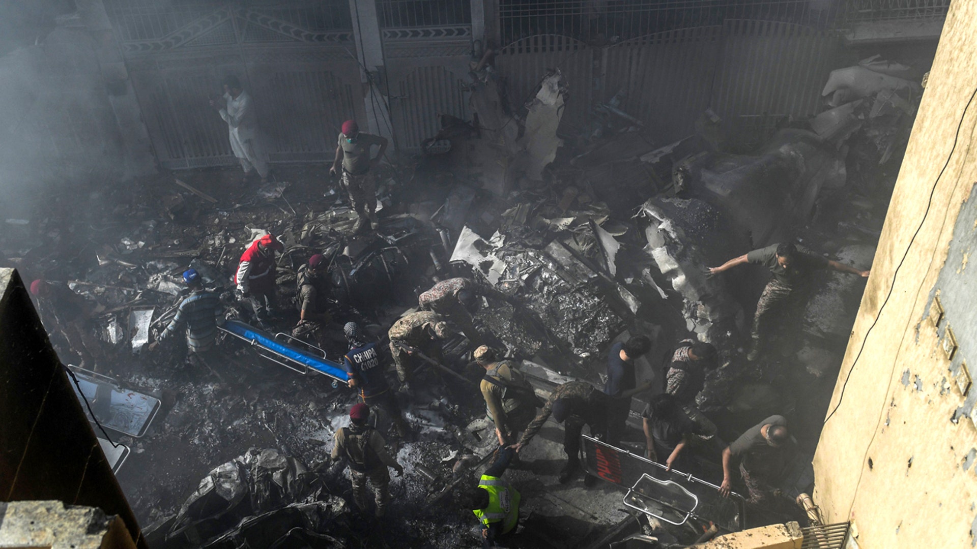 Rescue workers search for victims at the site after a Pakistan International Airlines aircraft crashed at a residential area in Karachi on May 22, 2020. A Pakistani passenger plane with nearly 100 people on board crashed into a residential area of the southern city of Karachi. (Photo by Asif HASSAN / AFP)