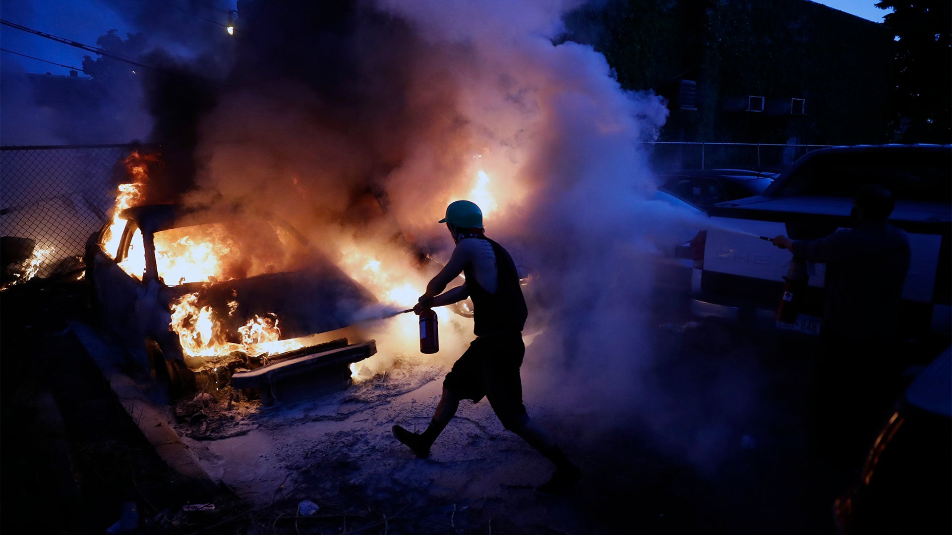 People attempt to extinguish cars on fire Friday night in Minneapolis.