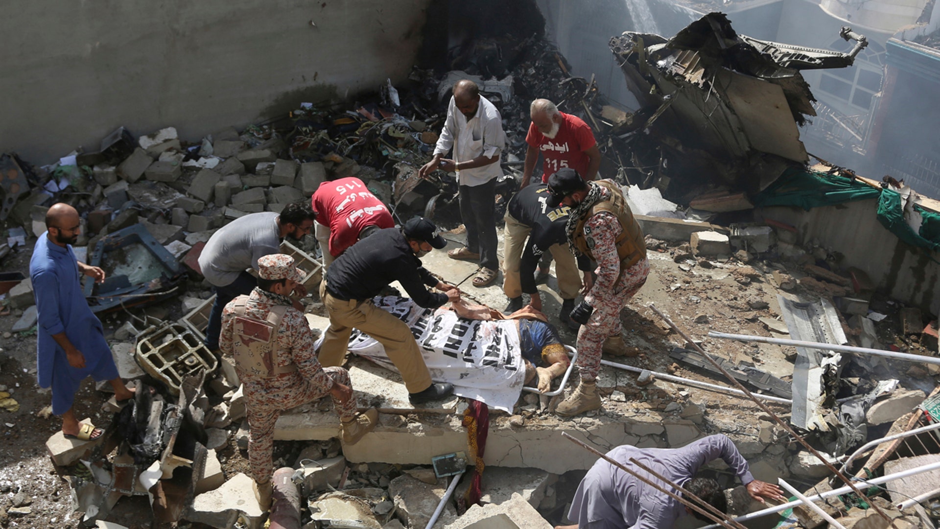 Volunteers cover the dead body of a plane crash victim at the site of the crash in Karachi, Pakistan, Friday, May 22, 2020. (AP Photo/Fareed Khan)
