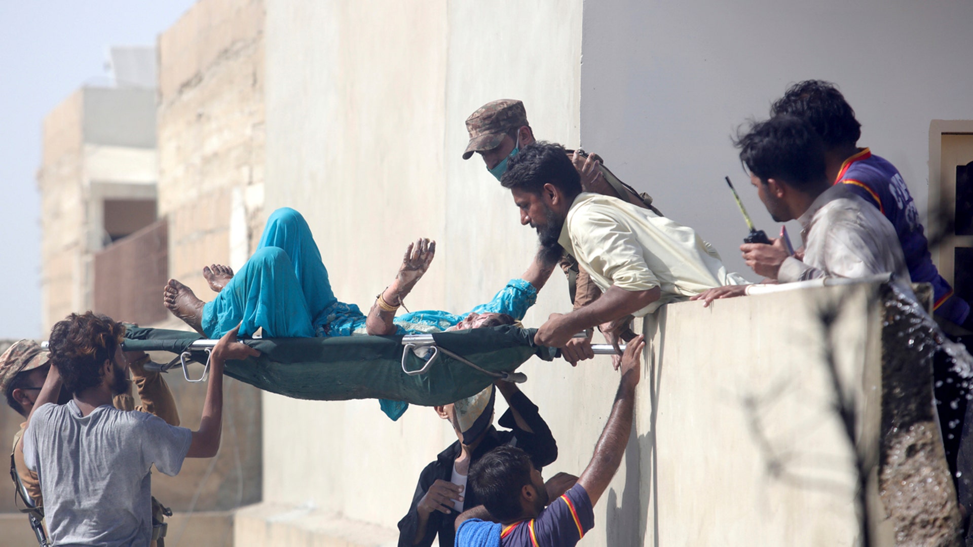 Volunteers carry an injured person at the site of a plane crash in Karachi, Pakistan, Friday, May 22, 2020. (AP Photo/Fareed Khan)
