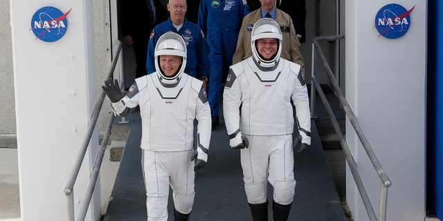 NASA astronauts Douglas Hurley, left, and Robert Behnken wave as they walk out of the Neil A. Armstrong Operations and Checkout Building on their way to Pad 39-A, at the Kennedy Space Center in Cape Canaveral, Fla., Wednesday, May 27, 2020.  (AP Photo/John Raoux)