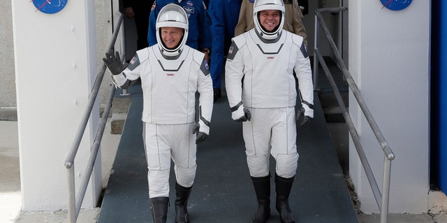 NASA astronauts Douglas Hurley, left, and Robert Behnken wave as they walk out of the Neil A. Armstrong Operations and Checkout Building on their way to Pad 39-A, at the Kennedy Space Center in Cape Canaveral, Fla., Wednesday, May 27, 2020. (AP Photo/John Raoux)