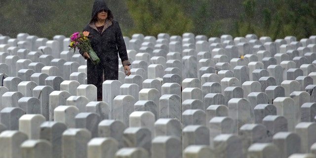 A woman looks for a grave in the rain as she visits Cape Canaveral National Cemetery for Memorial Day