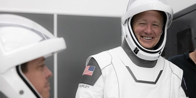 This Thursday, March 19, 2020 photo made available by SpaceX shows NASA astronauts Bob Behnken and Doug Hurley during flight simulator testing at the Kennedy Space Center in Cape Canaveral, Fla., with SpaceX teams in Firing Room 4 at NASA's Kennedy Space Center, SpaceX's Mission Control in Hawthorne, Calif., and NASA flight controllers in Mission Control Houston, for a full simulation of launch and docking of the Crew Dragon spacecraft.