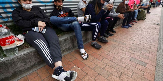 In this April 30, 2020 photo, Venezuelan migrants wait for buses that will transport them to the Venezuelan border, in Bogota, Colombia. The migrants want to return to their home country because they say they have not been able to find work in a country where businesses remain shuttered due to the new coronavirus pandemic and the strict stay-at-home order have limited their ability to help economically hurting relatives back home. (AP Photo/Fernando Vergara)