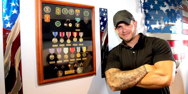 Colin Wayne next to medals he received for combat.