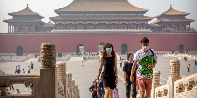 Visitors wearing face masks to protect against the new coronavirus walk through the Forbidden City in Beijing, Friday, May 1, 2020. (Associated Press)